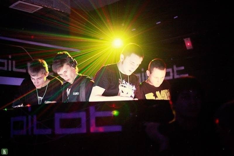 Four DJs performing under club lights