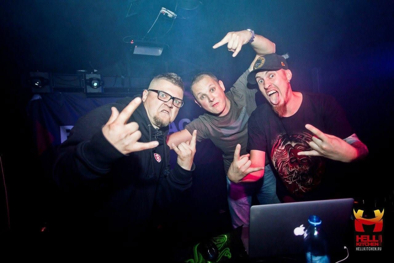 Three performers posing together behind a laptop